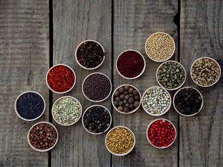 spices on a wooden background. Coriander, black pepper, paprika, mustard, turmeric, cumin, sumac, fenugreek, cloves, cubeb.