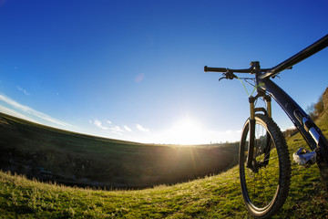 Fototapeta na wymiar Mountain bike on journeys. Going up hills on small roads between green fields with blue sky.