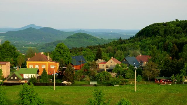 A village - a meadow in the foreground, a mountainous landscape in the background
