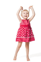 Cute smiling little girl in red dress posing at studio