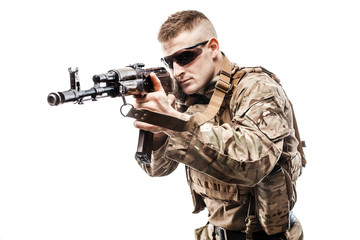 Studio shot of young serviceman in uniform holding machine gun and aiming on white background....