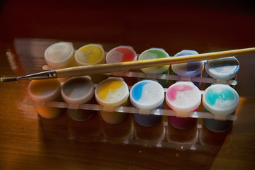 set of nine colors gouache paints in jars on wooden table