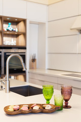 Modern designer chrome water tap against the background of new cabinets made of wood with a built-in oven