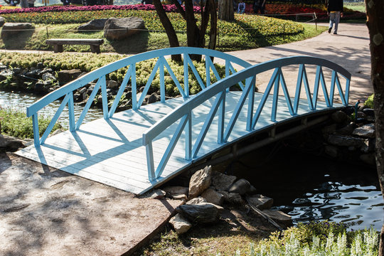 Beautiful small blue wooden bridge in the flower garden