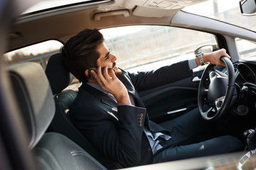 The attractive businessman, driving with a sense of urgency, deftly manages a phone call as he...