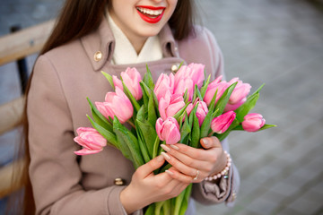 Happy smiling girl with spring tulips flowers outdoors