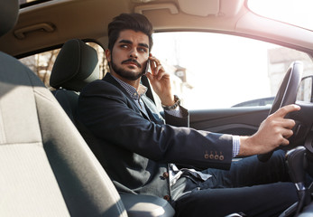 The attractive businessman, driving with a sense of urgency, deftly manages a phone call as he hurries to a crucial business meeting.