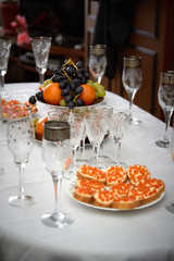 Festive wedding table, glasses of champagne, sandwiches with caviar, snacks, food, pineapples, hearts, love