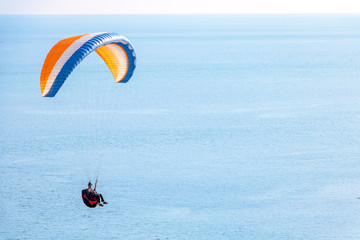 Sitting skydiver with a parachute flying over the sea with the horizon