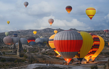 Colorful hot air balloons flying over the valley at Cappadocia, Turkey. Volcanic mountains in...