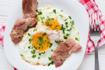 Fried eggs with bacon on white background