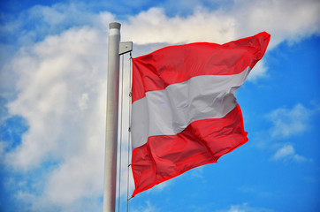Naklejka na ściany i meble Austrian Flag weht im Wind bei bewölktem Himmel