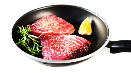 Raw tuna on a frying pan close up isolated on white background.