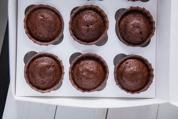 beautiful brown delicious chocolate muffins in a white box delivery food on wooden background close-up