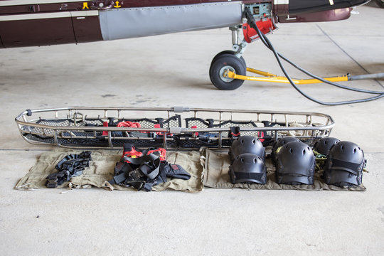 searh and rescue equipment arrange on ground before mission with helicopter background
