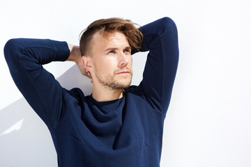 cool fashion guy looking away with hands behind head