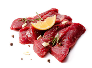 Pieces of meat with garlic and rosemary isolated on white background. Raw beef.