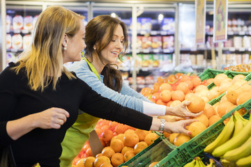 Customer And Saleswoman Choosing Fresh Oranges In Grocery Store
