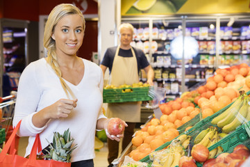 Smiling Customer Holding Apple In Supermarket