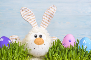 Toy little Easter bunny and Easter eggs on green grass. Easter concept.
