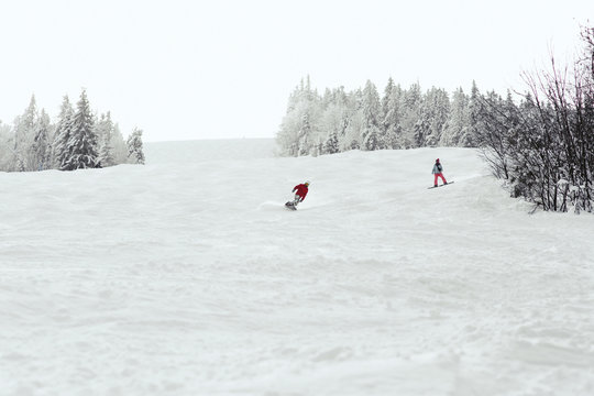Man and woman go down the hill on the snowboards