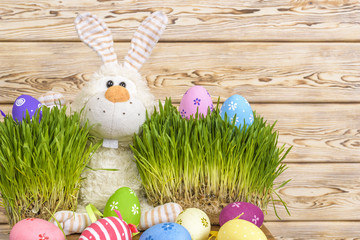 Toy little Easter bunny and Easter eggs on green grass. Easter concept.