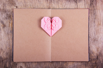 Heart origami and book with blank pages. Pink heart made of paper and diary. Copy space