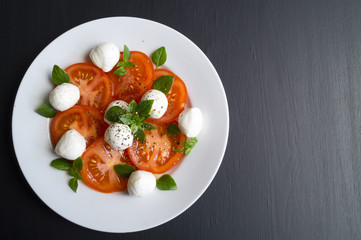 Caprese salad with ripe tomatoes and mozzarella with fresh Basil leaves. Italian food.
