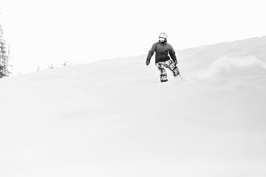 Black and white picture of man going dow the hill on his snowboard