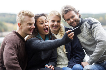Happy Woman With Friends Taking Self Portrait At Campsite