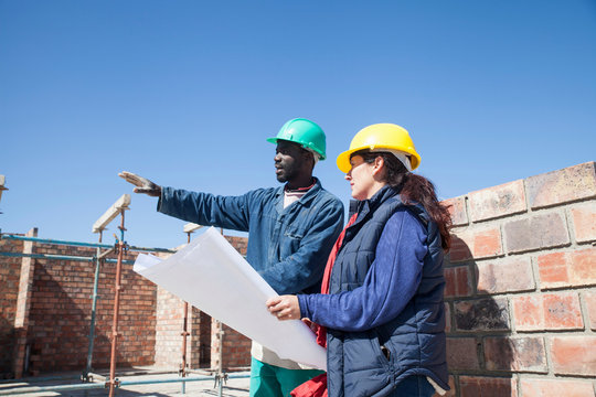 Site manager and builder looking at blueprint on construction site