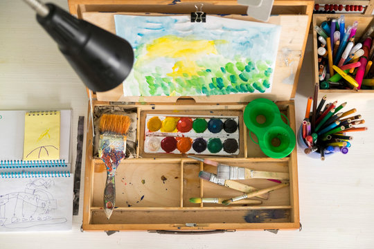 Box of paint, paintbrushes, drawing and assortment of colour pencils and painting tools