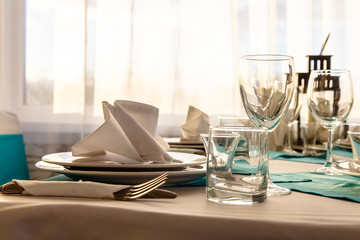 Linen napkin on a plate on the table covered with a white tablecloth.