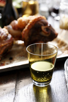 Pork hock on platter, sparkling drink in foreground, close-up