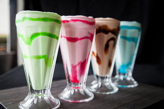 Row of four colourful milkshakes on table
