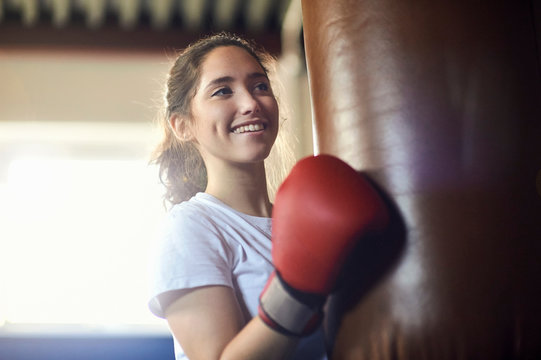 Young female boxer punching punch bag in gym
