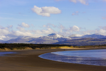 View of the snow-capped Snowdonia Mountain range from the beach at Llanddwyn, Newborough Warren, Isle of Anglesey, North Wales