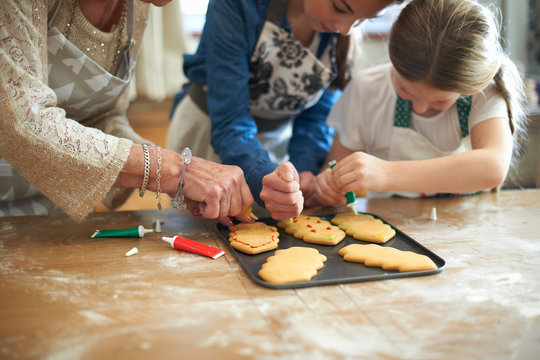 Cropped shot of senior woman and granddaughters decorating Christmas tree cookies