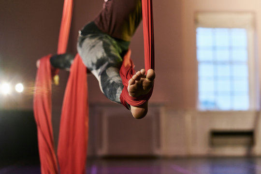 Waist down view of young female aerial acrobat practicing splits on silk rope