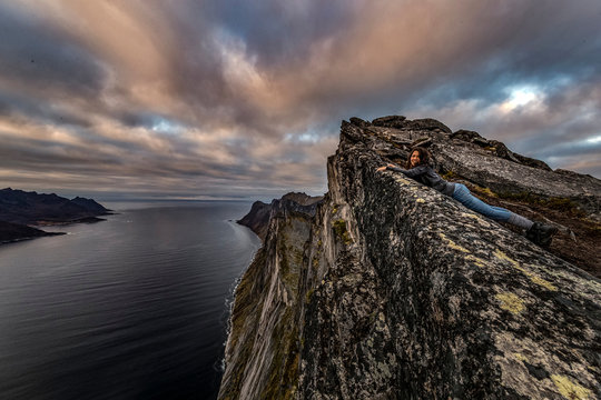 Woman looks out to sea from Segla Peak on Senja Island in autumn, Arctic Norway