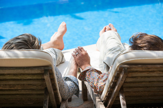Rear view of romantic male couple holding hands at poolside, Majorca, Spain