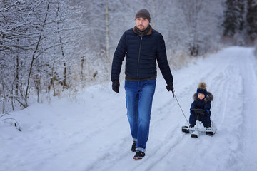 Little boy with father outdoor. Winter. Sled.