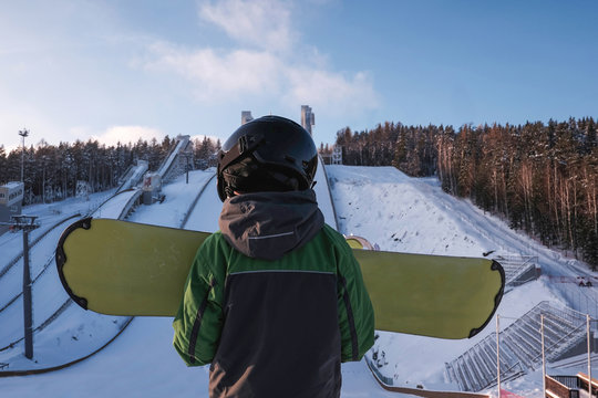 Rear view of boy with snowboard at top of ski slope