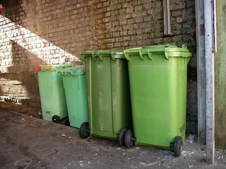 Grüne Mülltonnen vor alter Backsteinmauer einer Lagerhalle bei Sonnenschein im Hafenweg am Hafen...