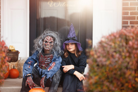 Friends dressed as witch and zombie, sitting on front step of home