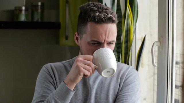 Young man drinking coffee and enjoying view from the window