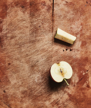 Overhead view of fresh halved apple and apple core on wooden cutting board