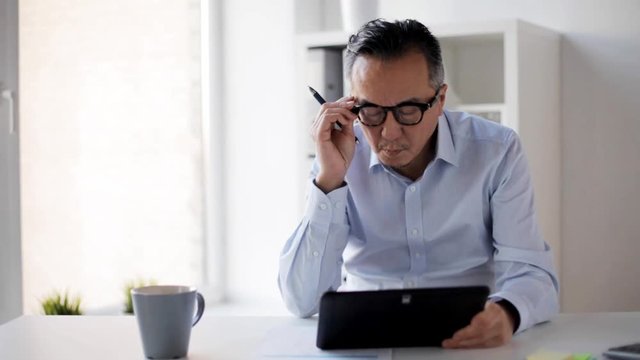 businessman with tablet pc and papers at office