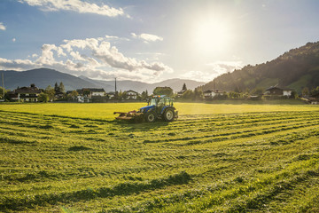 Fototapeta premium Summer evening landscape and tractor in harvest field ,Tirol, Austria