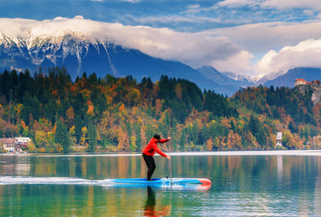 Paddle surfer training on Bled lake in Slovenia at Alps mountains background.